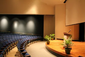 The OMA Auditorium with empty blue seats in front of the stage and podium.