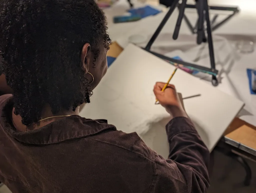 a woman sketching on a canvas during Art Night Out at OMA