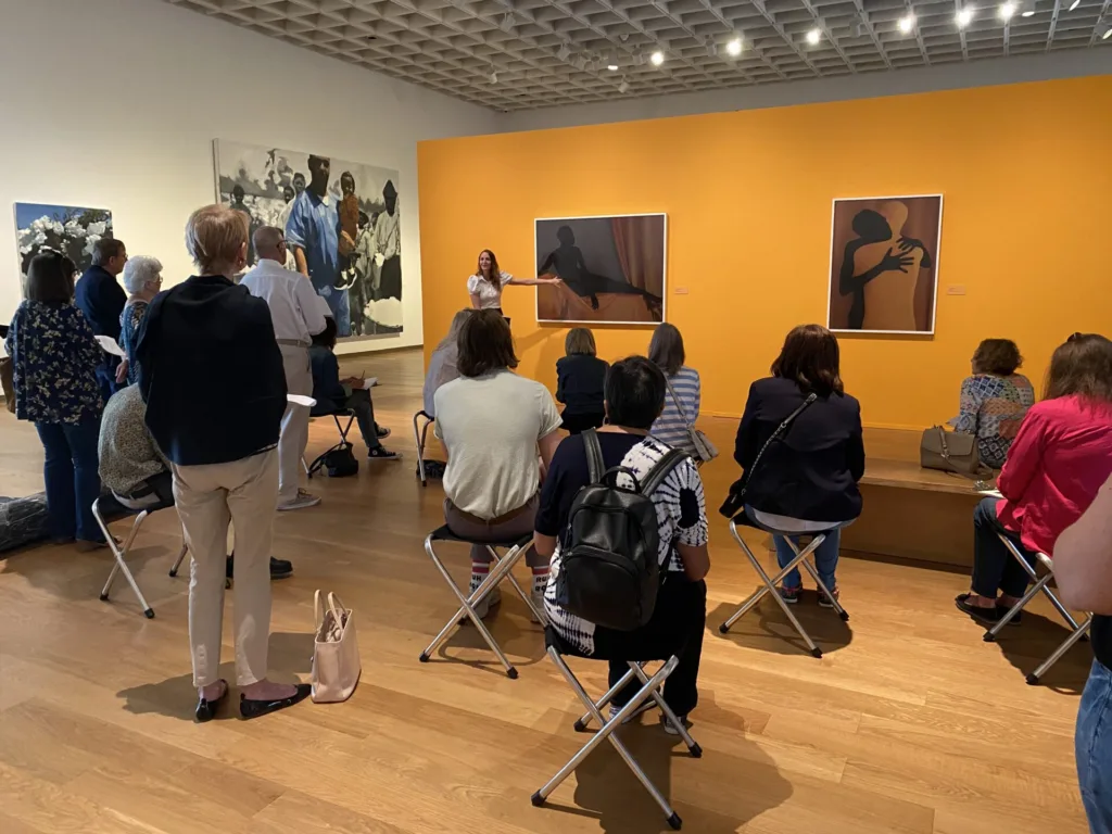 a group of people listening to a gallery talk at oma