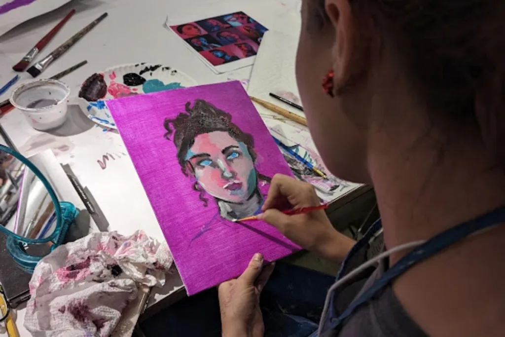 a teenage girl painting a picture of a young girl