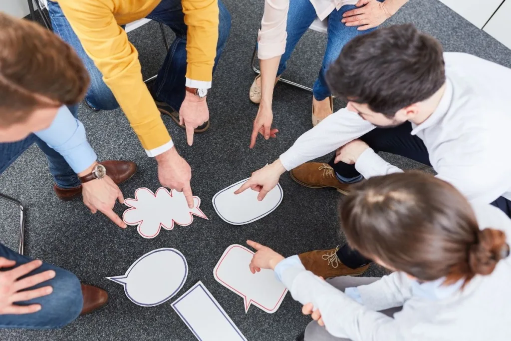 a corporate team at an event pointing to cut outs of paper