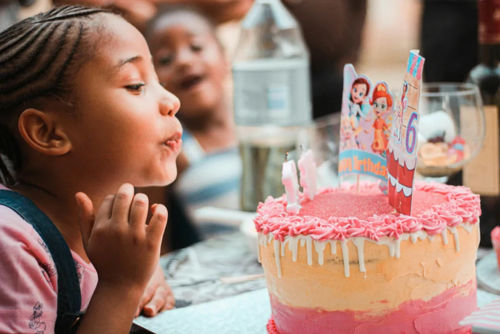 a young girl blowing out birthday candles on a cake