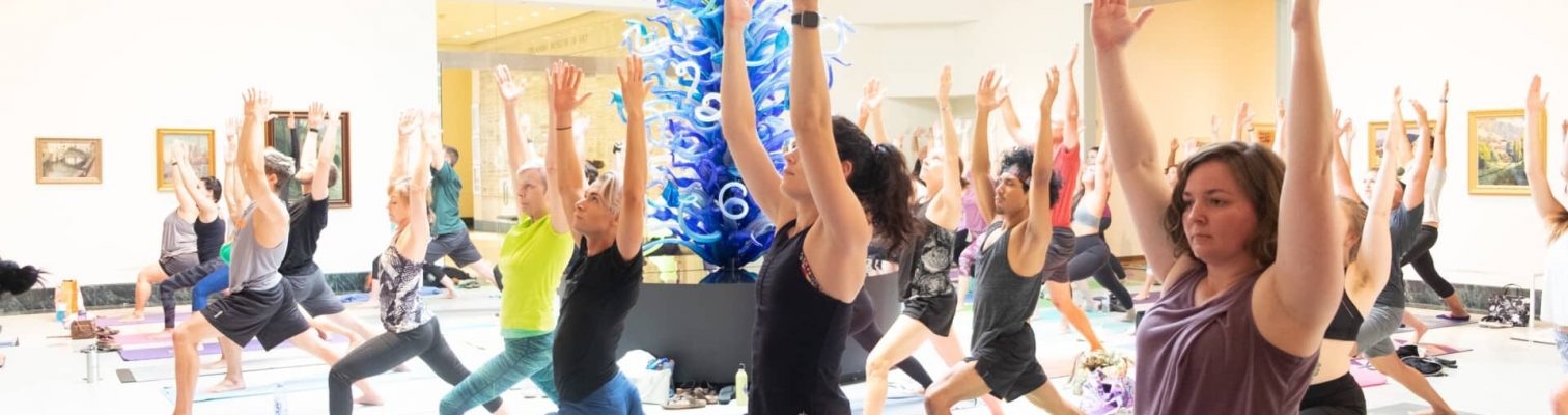 Adults doing yoga around an installation in an art gallery.