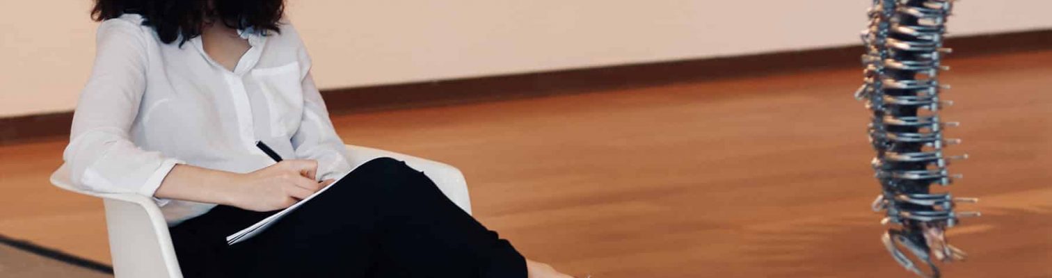 A woman sketching on a pad during a drawing class for adults.