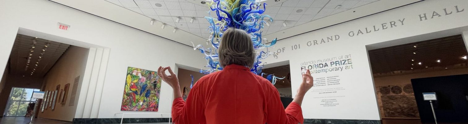 Back of an elderly woman meditating in an art gallery.