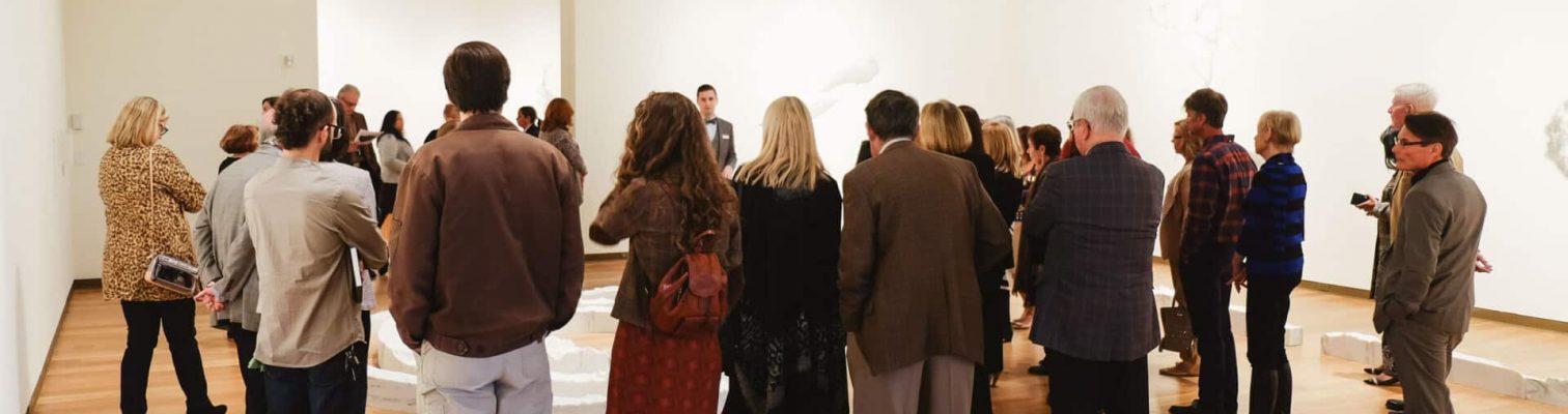 Adults gathered around a docent in a gallery during one of OMA's Highlights Tours.