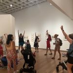 Mothers and children stretching their arms up in a gallery.